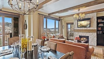 A dining area with a table set for four, a fireplace, and a large window with a view.