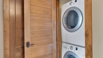 Un lavadero con dos lavadoras apiladas y una puerta de madera.