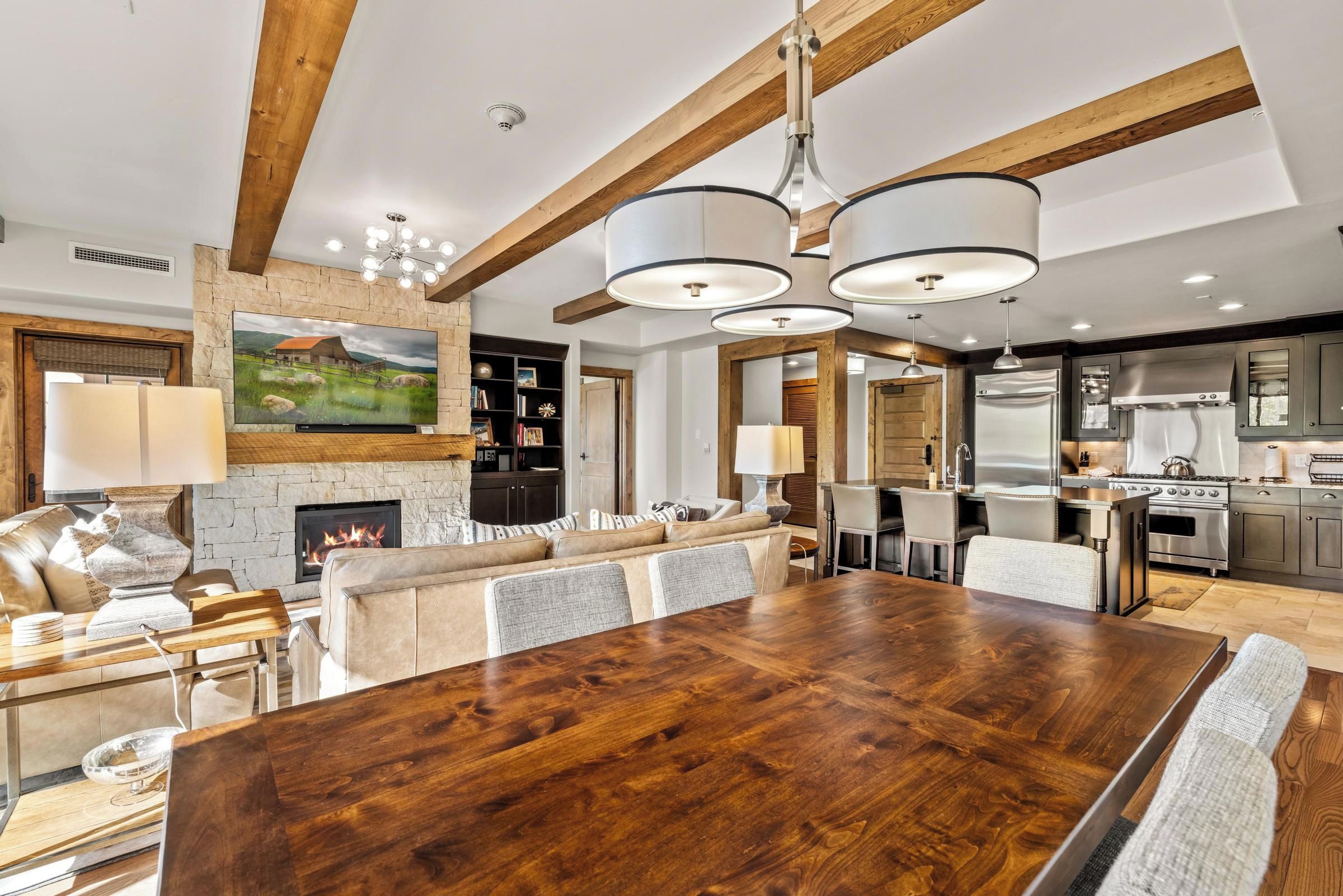 A spacious living area with a large wooden dining table, a fireplace, and a kitchen with modern appliances.