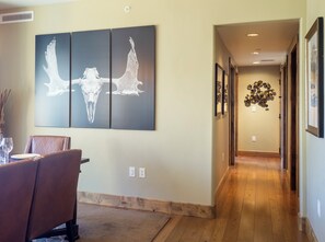 A hallway with a dining area featuring a brown leather chair and a table set with plates and glasses. - Edgemont Condominiums (Steamboat Springs)