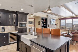 A modern kitchen with a central island, built-in appliances, and a dining area with a view. - Edgemont Condominiums (Steamboat Springs)