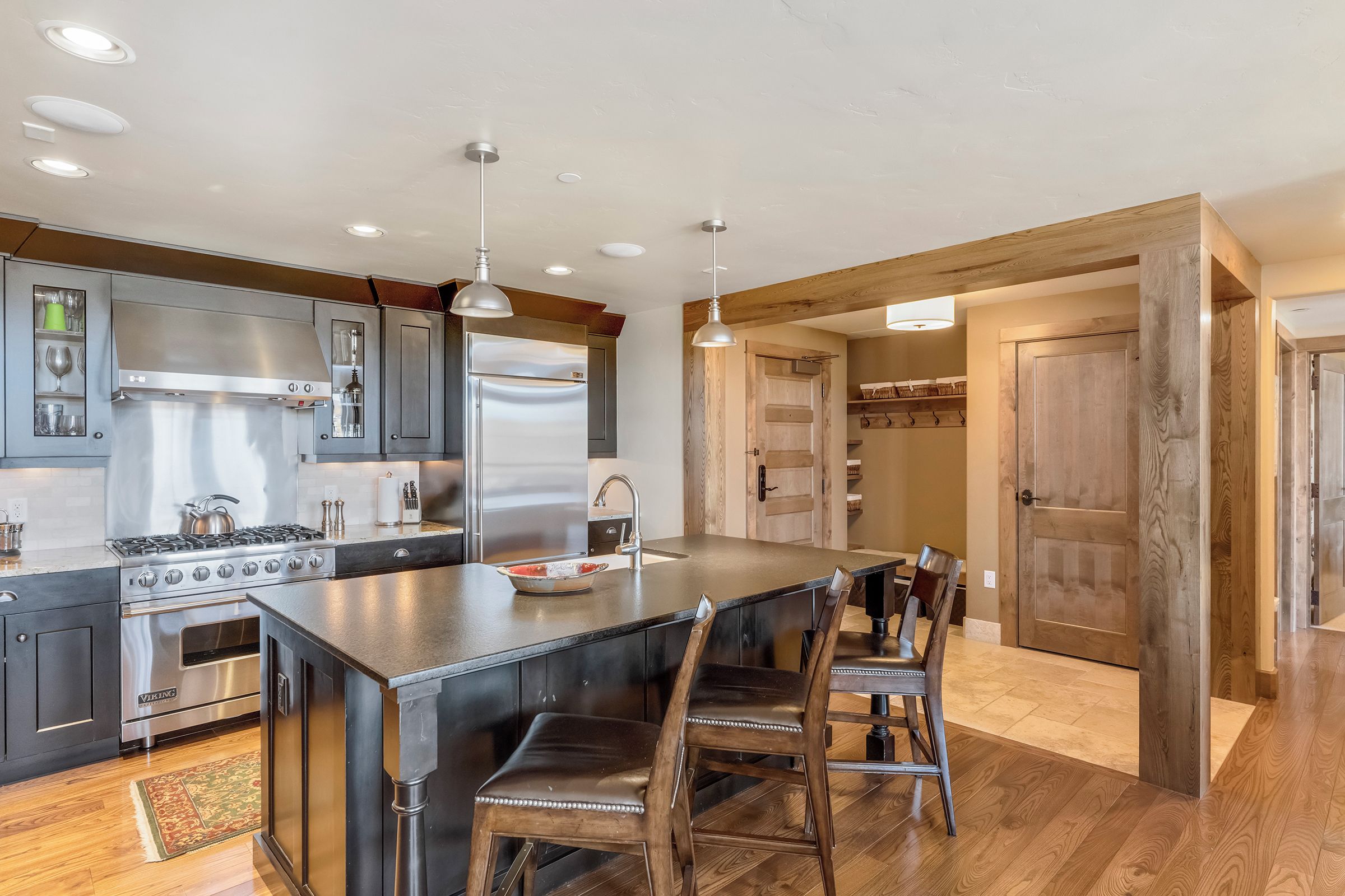 A modern kitchen with a large island, stainless steel appliances, and wooden flooring.