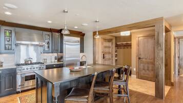 A modern kitchen with a large island, stainless steel appliances, and wooden flooring.