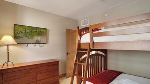 A bunk bed with a ladder, a wooden dresser, a lamp, and a painting on the wall. - Edgemont Condominiums (Steamboat Springs)