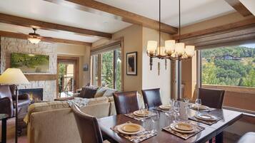 A dining area with a wooden table set for six, a fireplace, and a view of the outdoors.