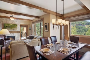 A dining area with a wooden table set for six, a fireplace, and a view of the outdoors. - Edgemont Condominiums (Steamboat Springs)