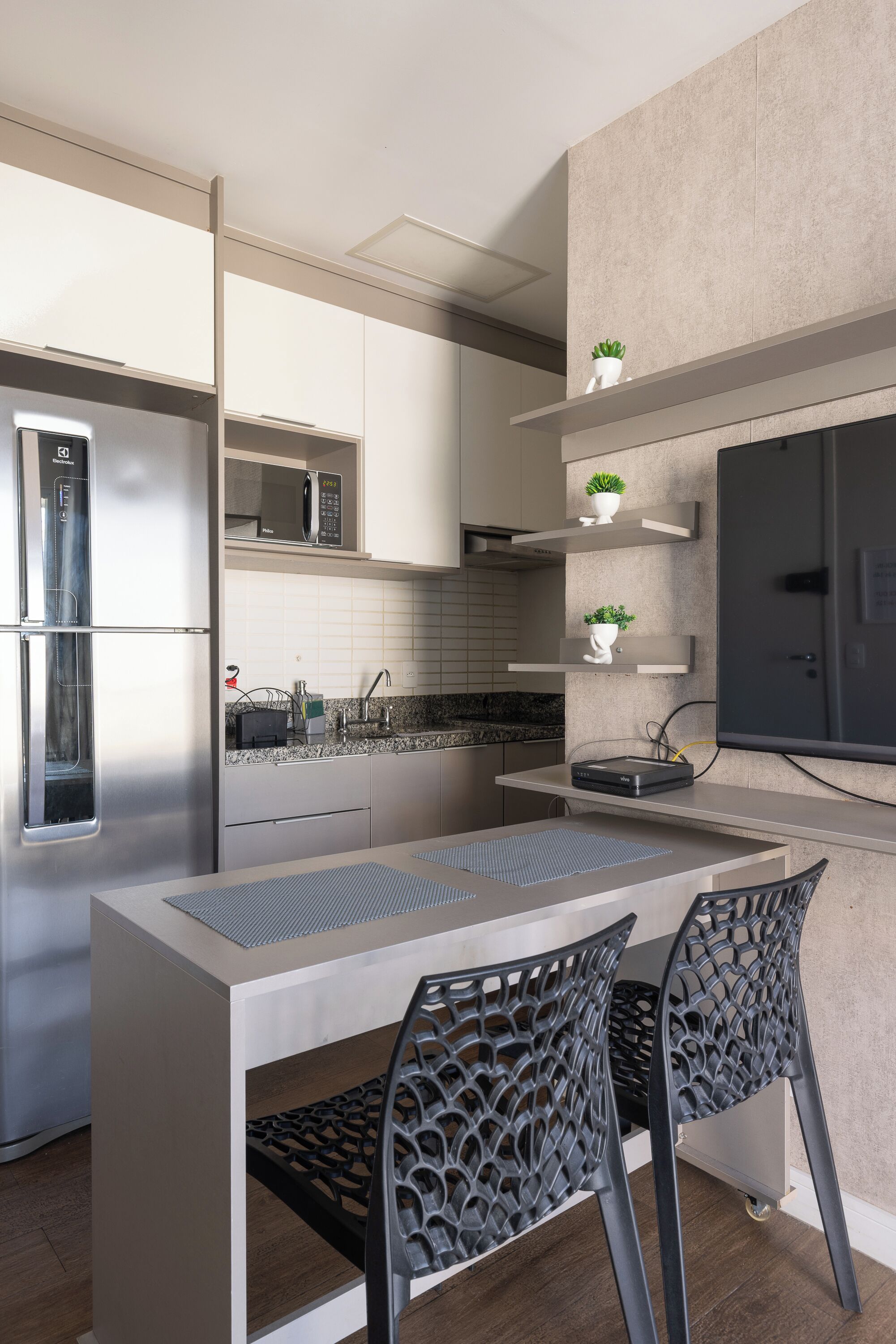 A modern kitchen with a built-in microwave, stainless steel refrigerator, and a dining area with a table and chairs.