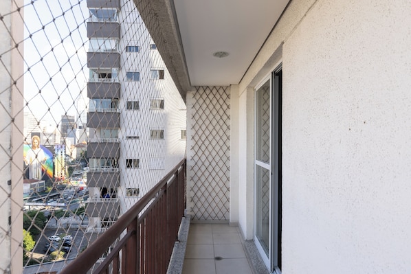 A balcony with a view of a high-rise building, a metal fence, and a tiled floor. - StayHome - Centro Histórico - Gym & Pool (São Paulo)