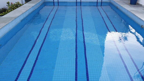Una piscina con agua azul cristalina y bordes de azulejos.