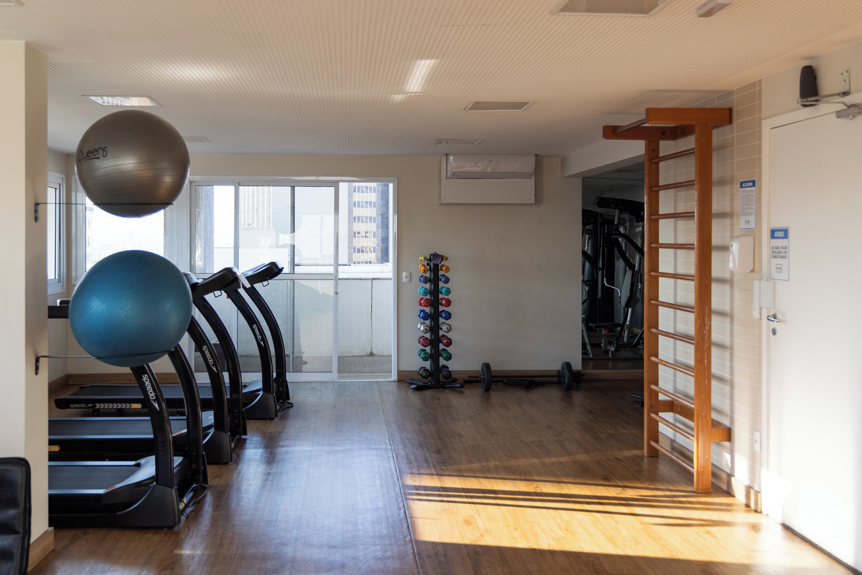 A gym with treadmills, exercise balls, and a rack of dumbbells.
