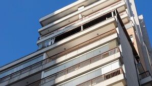 Un edificio de varios pisos con balcones, ventanas amplias y cielo despejado.