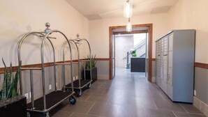 A hallway with a reception area, including a counter, a plant, and a refrigerator. - Chestnut Chateau at the Brent Lofts (Pensacola)