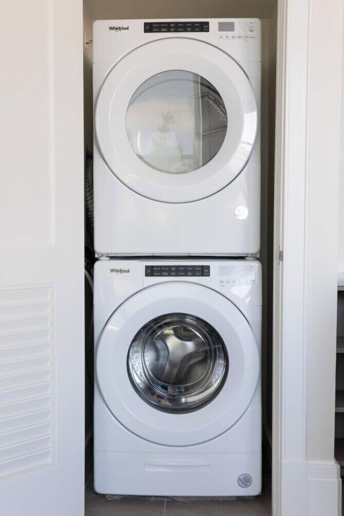 Two stacked Whirlpool washing machines in a laundry room.