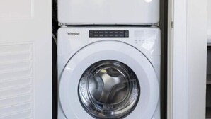 Two stacked Whirlpool washing machines in a laundry room. - Chestnut Chateau at the Brent Lofts (Pensacola)