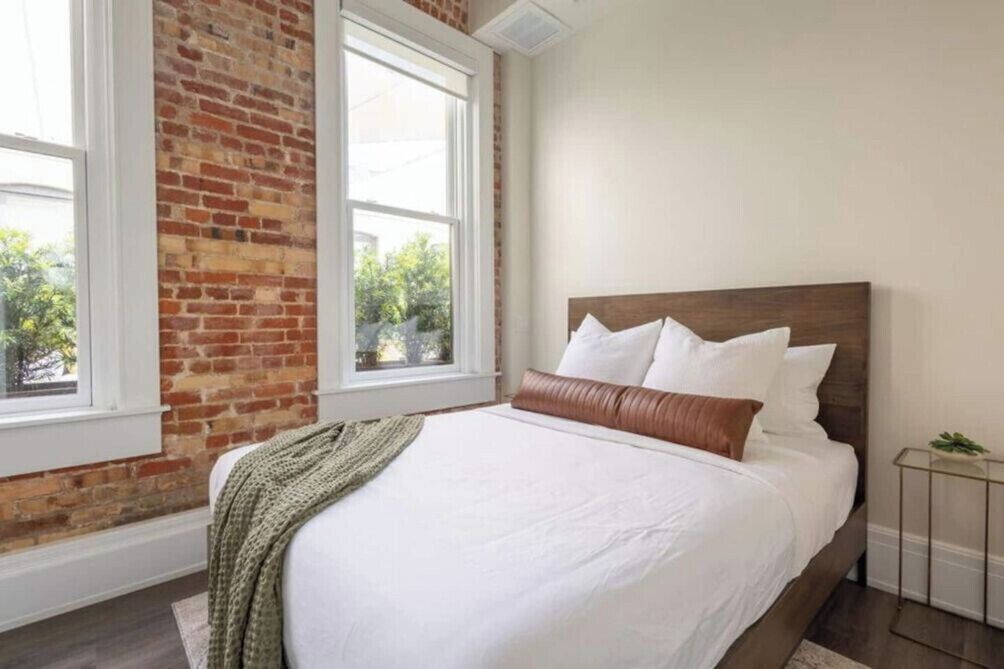 Een slaapkamer met een groot bed, een bakstenen muur en een raam.