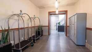 A hallway with a reception desk, a plant, a cart, and a filing cabinet. - Pura Vida at The Brent Lofts (Pensacola)