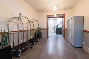 A hallway with a reception desk, a plant, a cart, and a filing cabinet. - Pura Vida at The Brent Lofts (Pensacola)