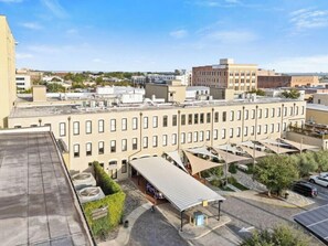 A multi-story building with a flat roof, a covered outdoor seating area, and a parking lot. - Pura Vida at The Brent Lofts (Pensacola)