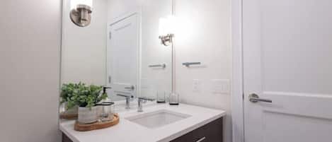 A bathroom with a white sink, dark-toned cabinet, and a door.