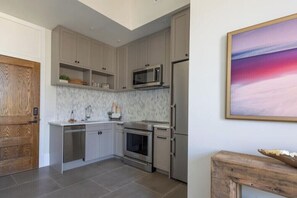 A modern kitchen with grey cabinetry, stainless steel appliances, and a marble backsplash. - Pura Vida at The Brent Lofts (Pensacola)