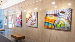 A hallway with artwork on the walls, benches, and a tiled floor. - The Brent Lofts Southern Comfort (Pensacola)