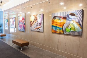 A hallway with artwork on the walls, benches, and a tiled floor. - The Brent Lofts Southern Comfort (Pensacola)