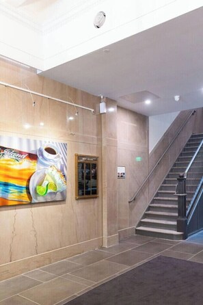 A hotel lobby with a marble wall, a staircase, and a large poster. - Modern Loft, Historic Streets- 2 bed/2 bath (Pensacola)