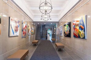 A hallway with artwork on the walls, benches, and a staircase in the background. - Modern Loft, Historic Streets- 2 bed/2 bath (Pensacola)