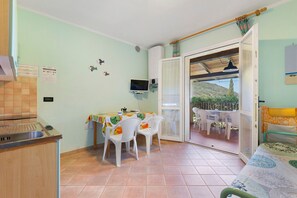 A small kitchen with a dining area, a TV, and a view of the outdoors. - Nisportino Vista Mare Apartment with Sea View, Wi-Fi, and Air Conditioning (Rio)
