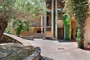 Ein Innenhof mit Steinmauer, Wasserspiel und einem Gebäude mit Balkon.