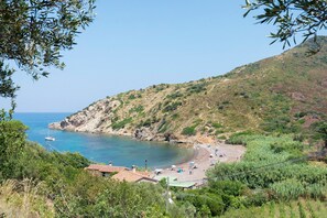 Eine Küstenlandschaft mit Strand, einem kleinen Gebäude und hügeliger Kulisse.