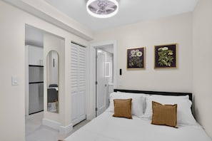 A bedroom with a bed, two pillows, a wardrobe, and a mirror. - Cozy-Luxe Jr 1BR Apt | Freshly Remodeled & Stylish (Miami Beach)