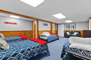 A room with four beds, wooden walls, a ski patrol sign, and directional signs for 'Avalanche' and 'Upper Ravine'. - CannonView Lodge (Littleton)