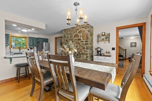 A dining area with a stone pillar, wooden chairs, and a chandelier. - CannonView Lodge (Littleton)