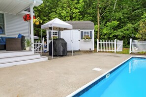 A backyard with a swimming pool, a covered grill, and a fenced area with a house. - CannonView Lodge (Littleton)