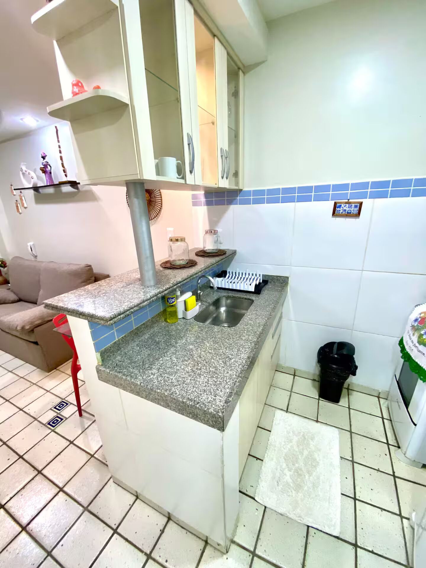 A compact kitchen with a granite countertop, a sink, and a tiled backsplash.