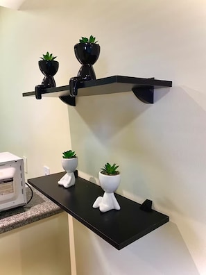 A black wall-mounted shelf with two potted plants and a white appliance on a countertop. - Apartment 108 beachfront (Natal)