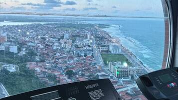 Esteira numa sala com uma janela ampla com vista para a paisagem costeira da cidade.