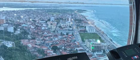 A treadmill in a room with a large window overlooking a coastal cityscape.