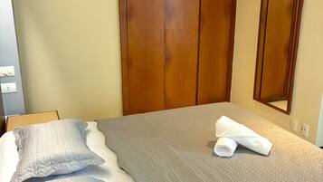 Quarto de hotel com cama, guarda-roupa de madeira, ar condicionado e espelho.