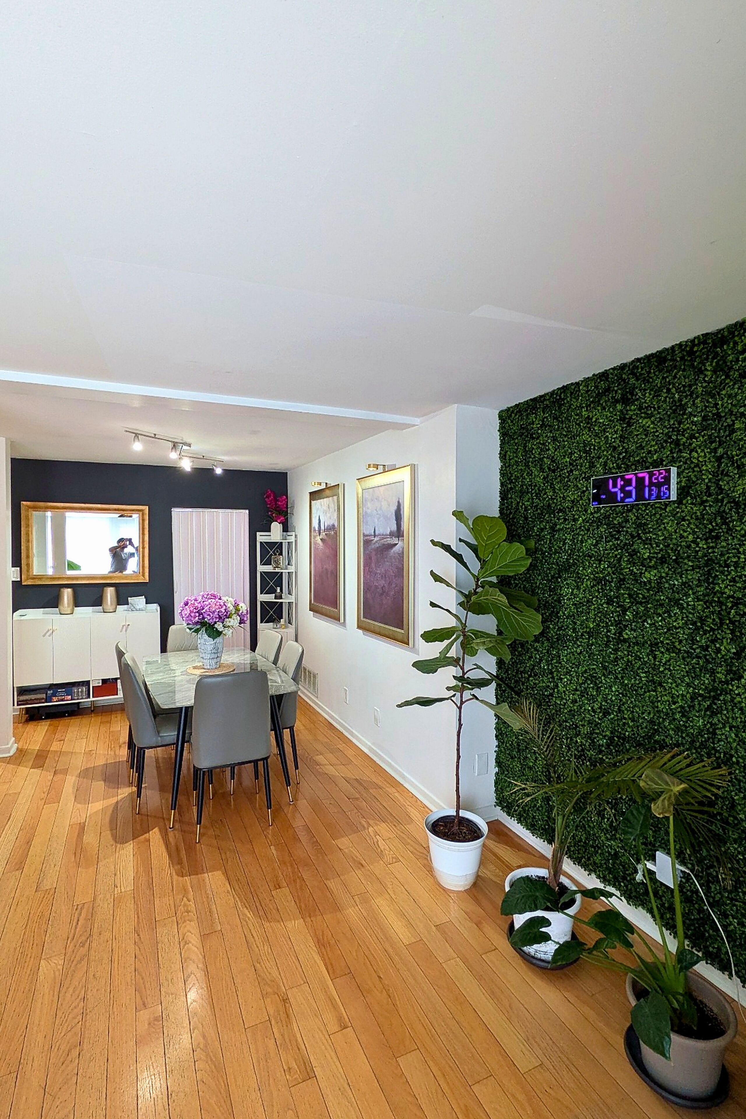 Un espace repas moderne avec un plancher en bois, une table en verre et des chaises grises.