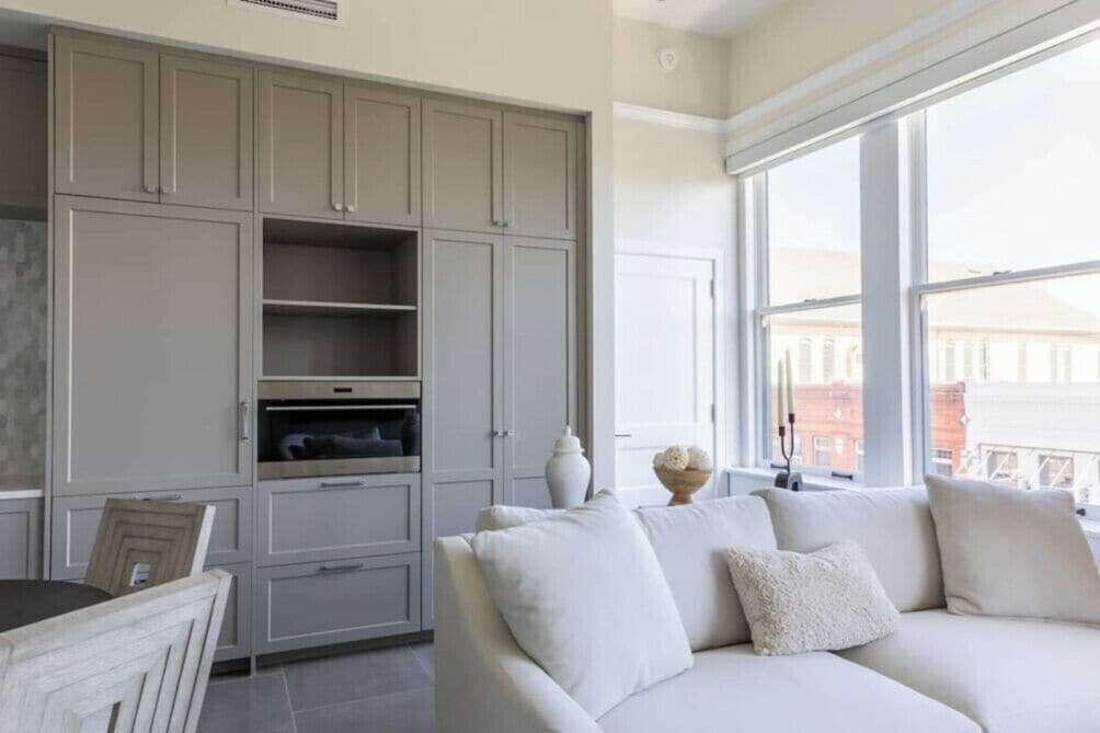 Un interior moderno con un sofá, armarios y una ventana con vistas.