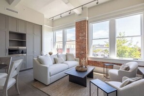 Ein zeitgemäßer Wohnraum mit Küche, einem weißen Sofa, einem Couchtisch und einer Ziegelsäule.