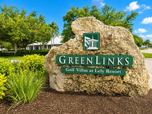 Schild für GreenLinks Golf Villas am Lely Resort, mit Logo und Text vor einem Steinuntergrund.