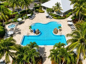 Ein großer Swimmingpool, umgeben von Palmen und Liegestühlen.