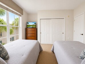 Ein Schlafzimmer mit zwei Betten, einem Schminktisch, einem Fernseher und einer Tür.