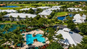 A resort with multiple buildings, a large swimming pool, and palm trees. - The Fairway Retreat at GreenLinks (Naples)