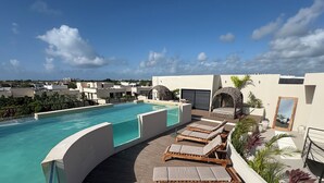 A rooftop pool area with lounge chairs and a view of the cityscape. - Studio in the heart of Tulum with rooftop pool - Solum Living (Tulum)