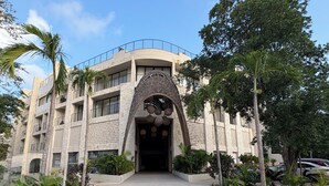 A multi-story building with a distinctive entrance featuring a decorative archway. - Studio in the heart of Tulum with rooftop pool - Solum Living (Tulum)