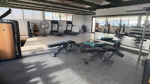 A gym with treadmills, weight machines, and a mirror reflecting the equipment. - Studio in the heart of Tulum with rooftop pool - Solum Living (Tulum)